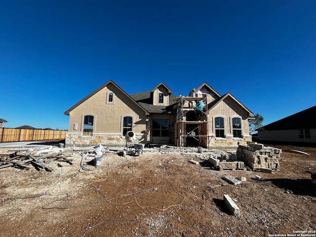 view of front of home with stone siding, fence, and stucco siding