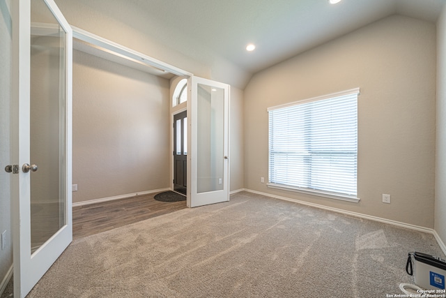 unfurnished bedroom with lofted ceiling, french doors, and carpet flooring