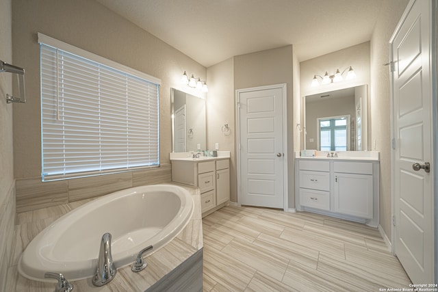 bathroom with tiled tub and vanity