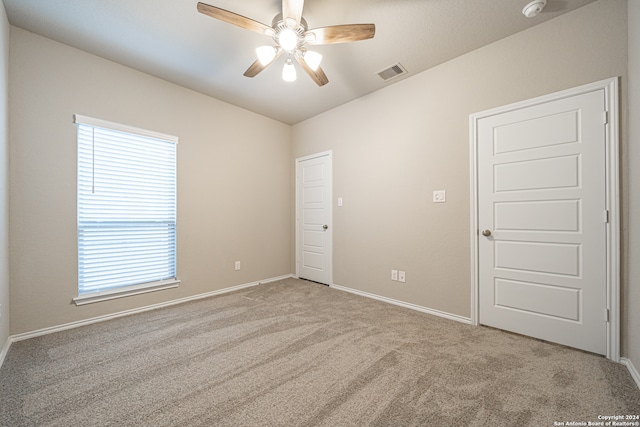 spare room featuring a wealth of natural light, ceiling fan, and light carpet