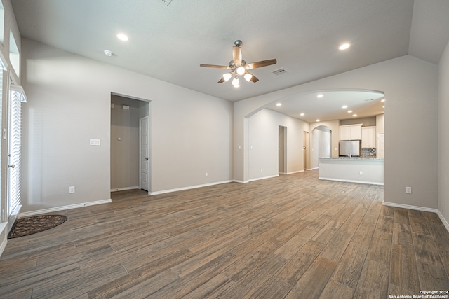 unfurnished living room featuring ceiling fan, vaulted ceiling, and dark hardwood / wood-style floors