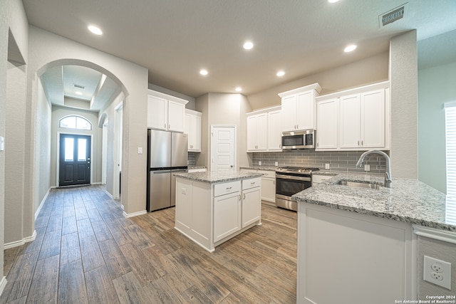 kitchen with sink, stainless steel appliances, white cabinets, and kitchen peninsula