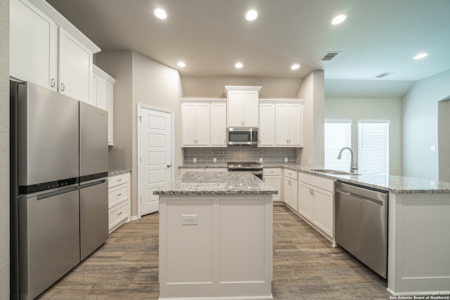 kitchen with appliances with stainless steel finishes, white cabinetry, a center island, and sink