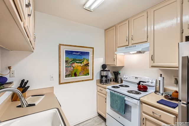 kitchen with stainless steel refrigerator, sink, white electric range, cream cabinetry, and light wood-type flooring