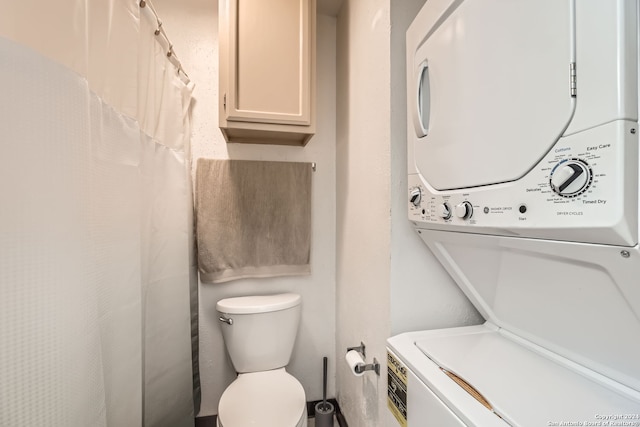 bathroom with stacked washer / drying machine and toilet