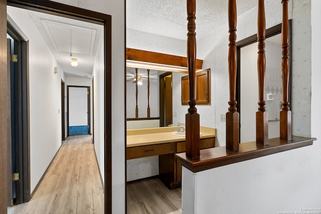 hall featuring sink, a textured ceiling, and light wood-type flooring