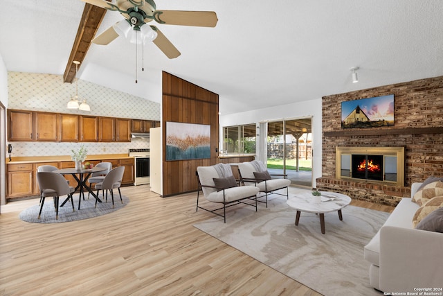 living room featuring high vaulted ceiling, ceiling fan, light wood-type flooring, a fireplace, and beam ceiling