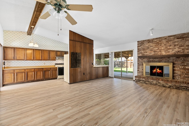 unfurnished living room featuring beamed ceiling, high vaulted ceiling, light hardwood / wood-style floors, and a brick fireplace