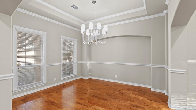 unfurnished dining area with a raised ceiling, hardwood / wood-style floors, ornamental molding, and a notable chandelier