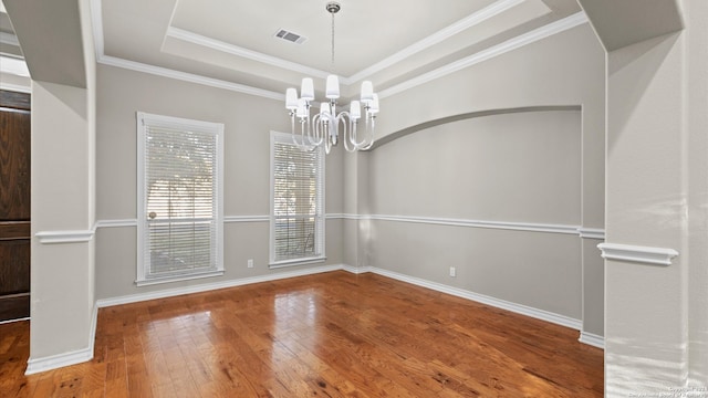 unfurnished dining area with hardwood / wood-style flooring, crown molding, a tray ceiling, and a notable chandelier