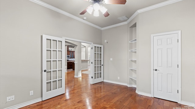 empty room featuring ceiling fan, french doors, ornamental molding, and hardwood / wood-style flooring