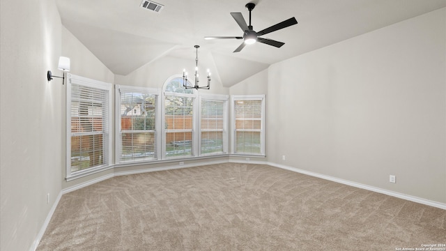 carpeted spare room featuring ceiling fan with notable chandelier and vaulted ceiling