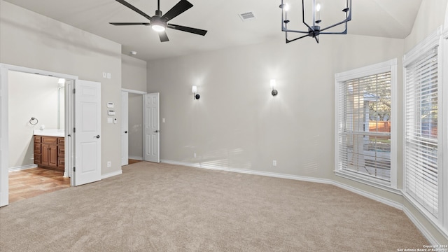 unfurnished bedroom with ensuite bathroom, high vaulted ceiling, light colored carpet, and an inviting chandelier