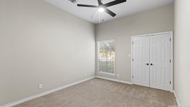 unfurnished bedroom featuring ceiling fan, light carpet, and a closet