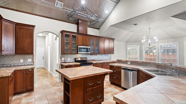 kitchen with high vaulted ceiling, sink, tasteful backsplash, a kitchen island, and stainless steel appliances