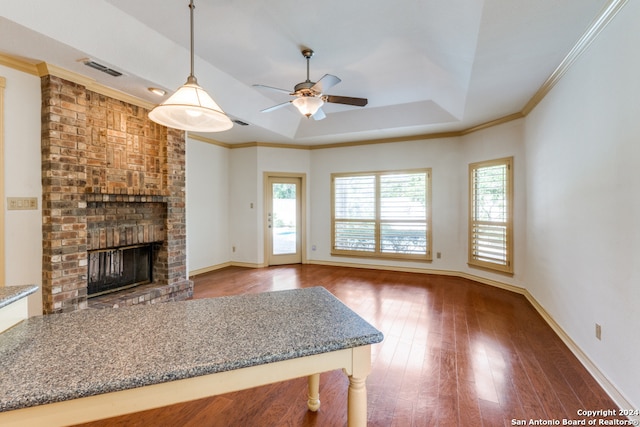 unfurnished living room featuring dark hardwood / wood-style floors, ceiling fan, crown molding, and a brick fireplace