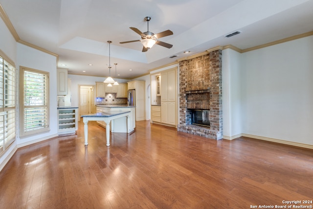 kitchen with a raised ceiling, hanging light fixtures, light hardwood / wood-style flooring, a kitchen island, and a kitchen bar