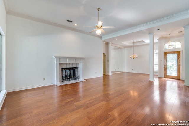 unfurnished living room featuring hardwood / wood-style flooring, ceiling fan with notable chandelier, ornamental molding, and a fireplace