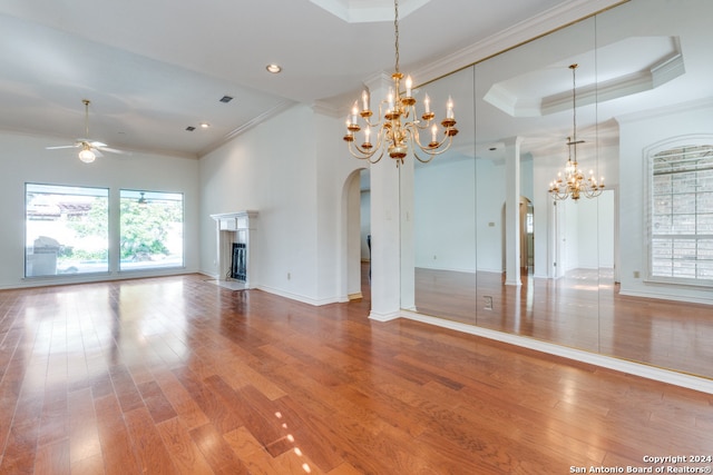 unfurnished living room with a fireplace, crown molding, hardwood / wood-style floors, and ceiling fan with notable chandelier