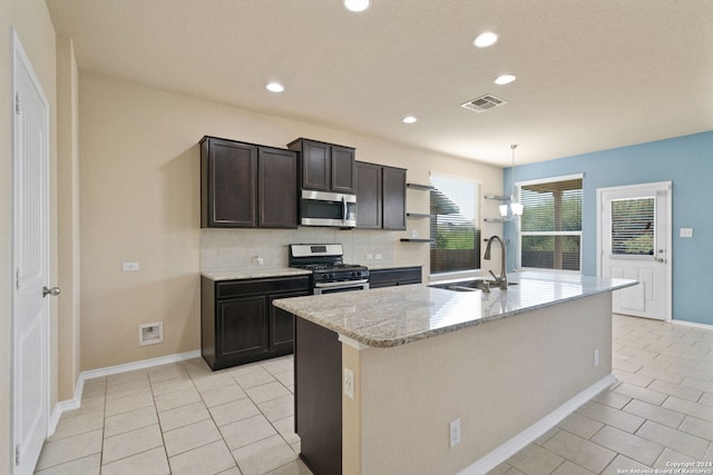 kitchen featuring light stone countertops, a kitchen island with sink, sink, and stainless steel appliances