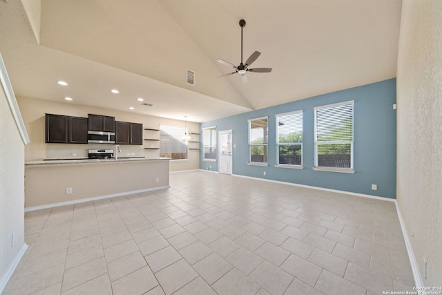 unfurnished living room featuring ceiling fan, light tile patterned floors, sink, and high vaulted ceiling