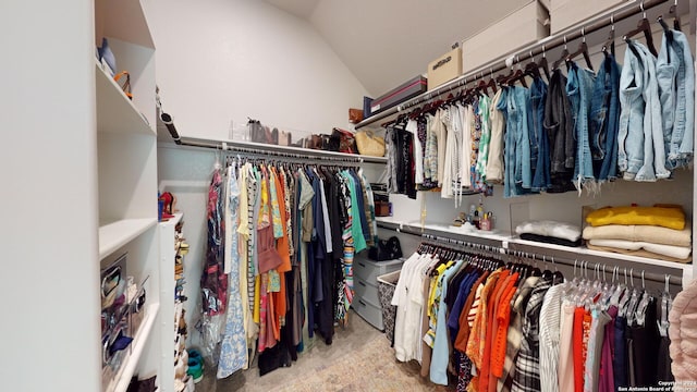 walk in closet with light colored carpet and vaulted ceiling