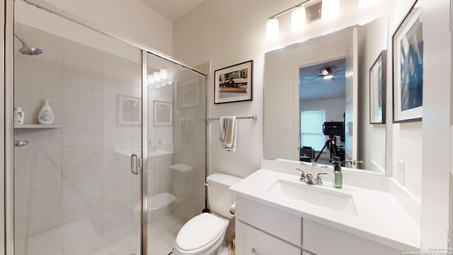 bathroom with vanity, ceiling fan, toilet, and a shower with door