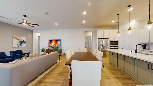 kitchen featuring pendant lighting, a center island, light hardwood / wood-style floors, white cabinetry, and stainless steel appliances