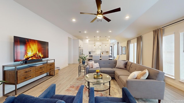 living room featuring a wealth of natural light, light hardwood / wood-style flooring, ceiling fan, and lofted ceiling