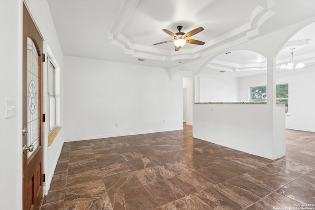 unfurnished living room with ceiling fan with notable chandelier and a raised ceiling