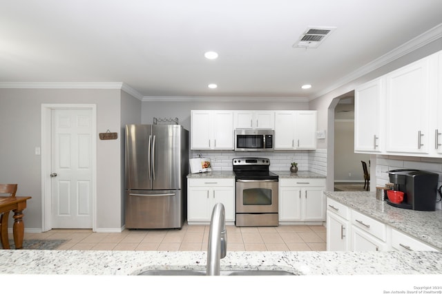 kitchen with stainless steel appliances, white cabinetry, and ornamental molding