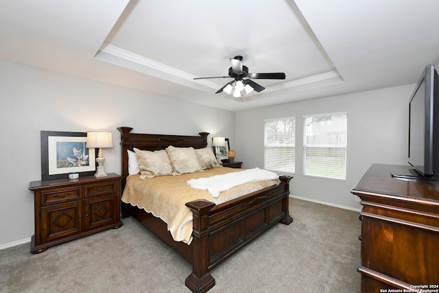 carpeted bedroom with a raised ceiling, ceiling fan, and ornamental molding