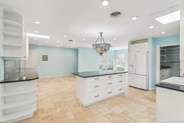 kitchen featuring backsplash, a skylight, white refrigerator with ice dispenser, pendant lighting, and white cabinets