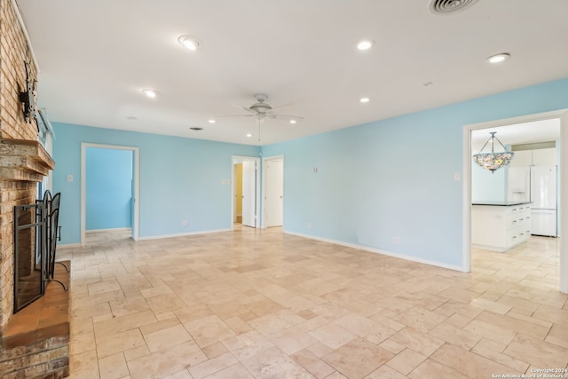 unfurnished living room featuring a fireplace and ceiling fan with notable chandelier