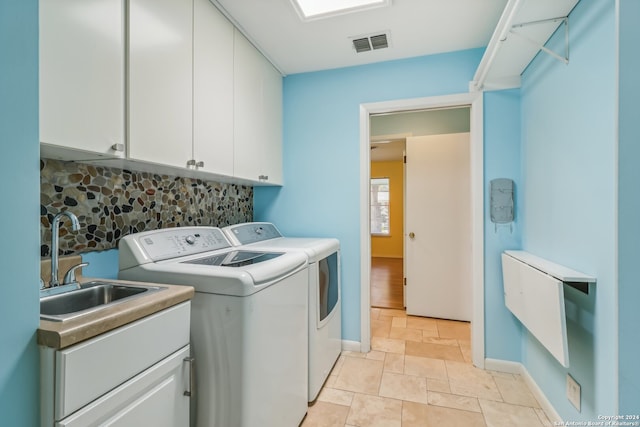 laundry area with cabinets, independent washer and dryer, and sink