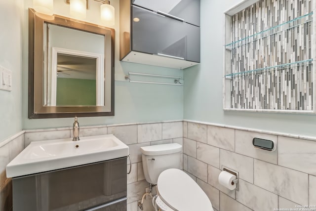 bathroom featuring vanity, tile walls, and toilet