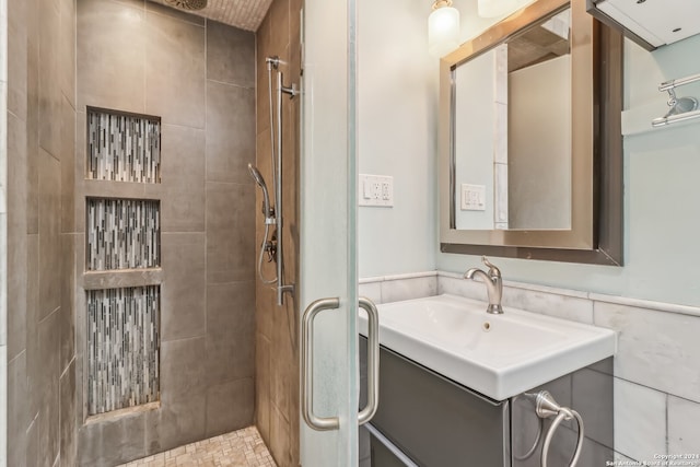 bathroom featuring a tile shower, vanity, and tile walls