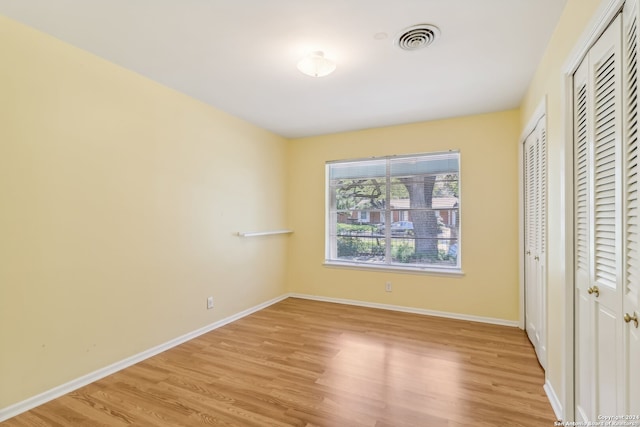 unfurnished bedroom featuring two closets and light hardwood / wood-style flooring