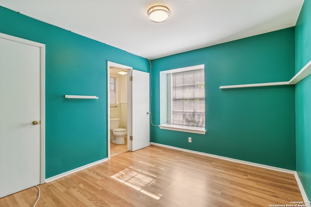 unfurnished bedroom featuring ensuite bathroom, a closet, and wood-type flooring