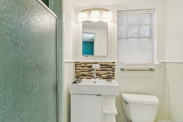 bathroom featuring vanity, tasteful backsplash, toilet, and walk in shower