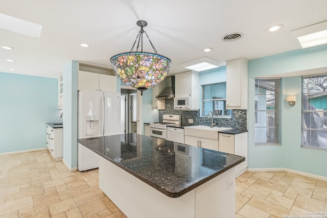 kitchen featuring white cabinets, hanging light fixtures, wall chimney range hood, and a kitchen island