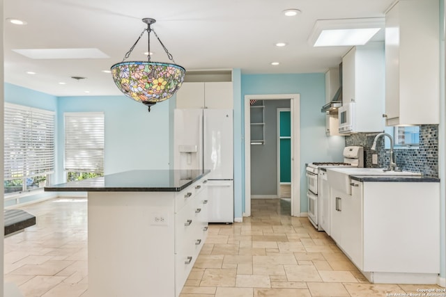 kitchen with a skylight, white cabinetry, white appliances, and decorative backsplash