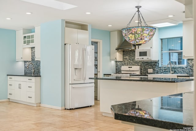 kitchen featuring wall chimney exhaust hood, decorative light fixtures, white cabinets, and white appliances