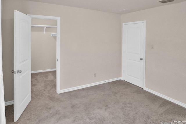 unfurnished bedroom featuring a spacious closet, light colored carpet, and a closet