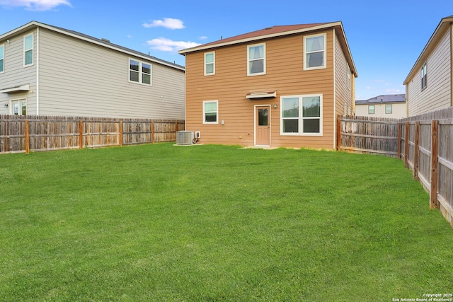 rear view of property featuring a yard and central air condition unit