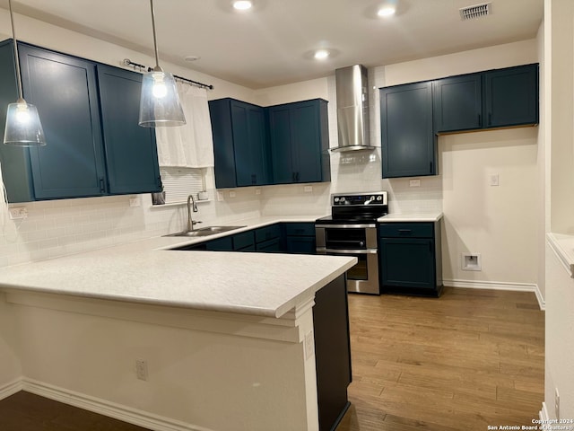 kitchen featuring decorative light fixtures, sink, range with two ovens, kitchen peninsula, and wall chimney range hood