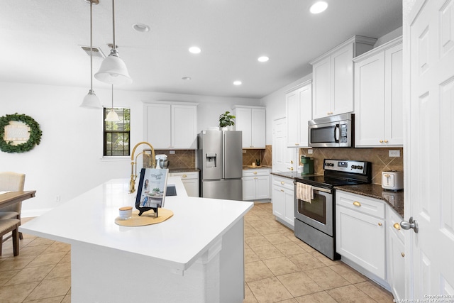 kitchen with appliances with stainless steel finishes, white cabinetry, and an island with sink