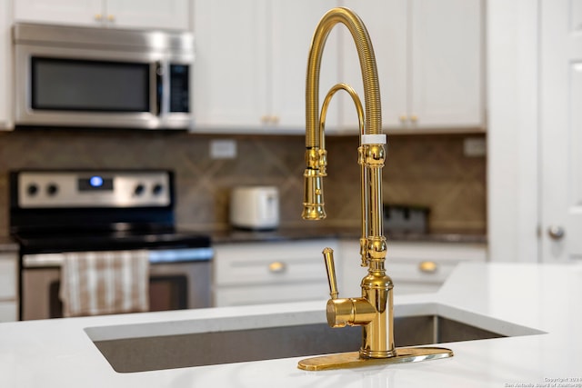 room details with decorative backsplash, white cabinetry, and stainless steel appliances