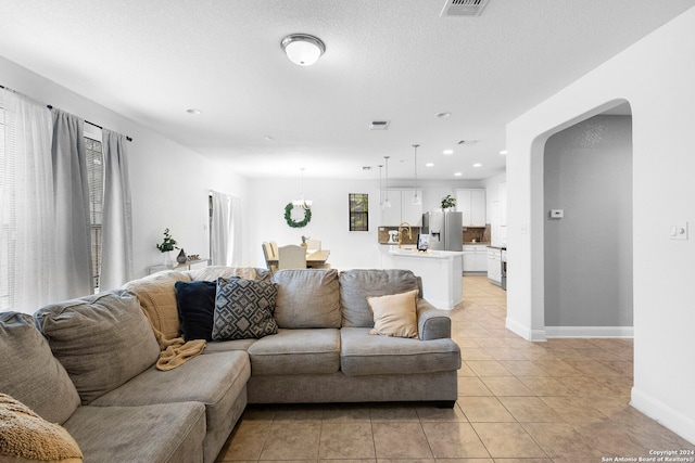 living room with a textured ceiling and light tile patterned flooring