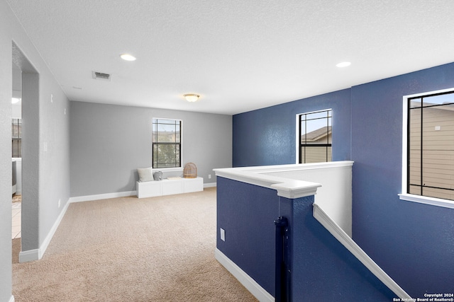 hall featuring carpet floors and a textured ceiling